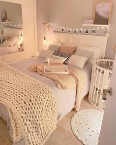 a white bed sitting in a bedroom next to a night stand with lights on it