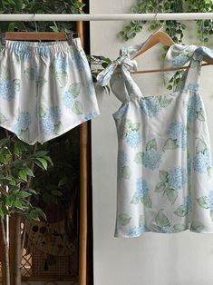 two blouses hanging on a clothes line next to a potted plant