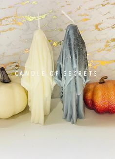 three candles in the shape of ghost and pumpkins on a white surface with text candle of secrets