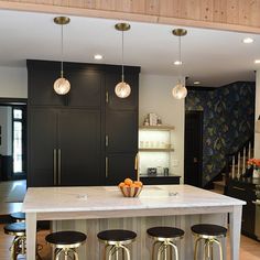 a kitchen island with stools and lights hanging from it's ceiling over the counter