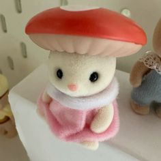 two small stuffed animals sitting next to each other on a shelf in front of a mushroom