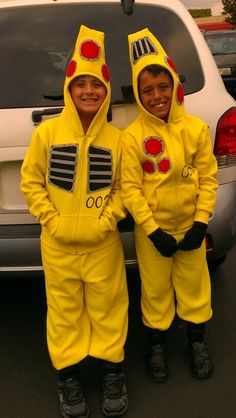 two children in yellow costumes standing next to a car