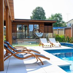 an empty swimming pool with chaise lounges in the foreground and a deck chair on the far side