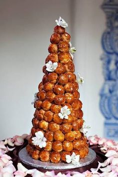 a tower of donuts on top of a table with pink and white flowers around it