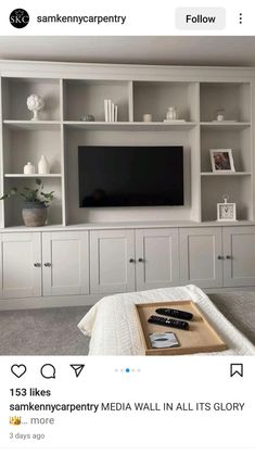 a white entertainment center with built in shelves and a flat screen tv mounted on the wall