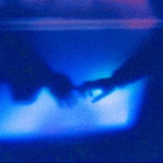 two hands touching each other in front of a television screen with blue and red lights