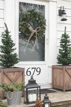 christmas wreaths and pine cones are on the front porch