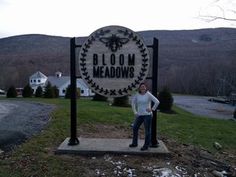 a woman standing in front of the bloom meadows sign