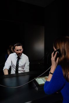 a man sitting in front of a mirror talking on a cell phone next to a woman