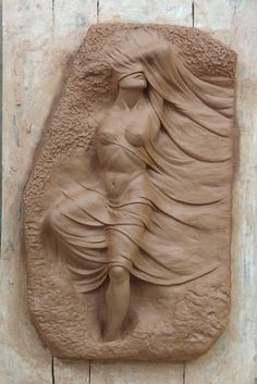 a clay sculpture of a woman with flowing hair on it's face and body