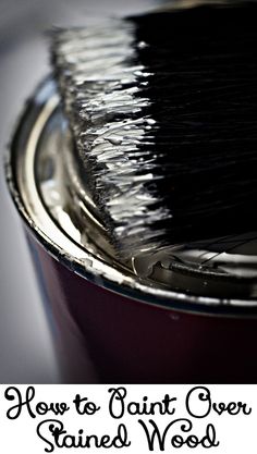 a close up of a paint brush in a can with the words how to paint over stained wood