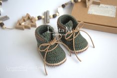 a pair of baby shoes sitting on top of a white table next to a box