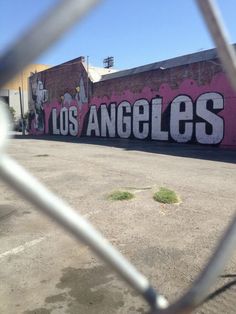 the word los angeles painted on a wall behind a chain link fence