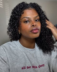 a woman with curly hair is looking at the camera and has her hand on her head