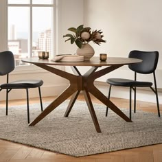 a table with chairs and a vase on top of it in front of a window