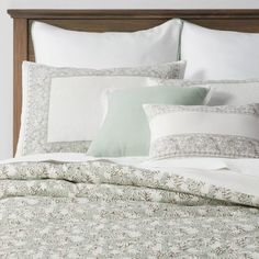 a bed with white and green pillows on top of it