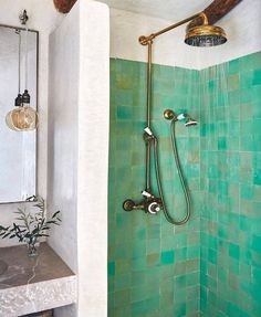 a bathroom with green tiles and a shower head