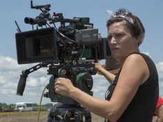 a woman standing next to a camera on top of a field