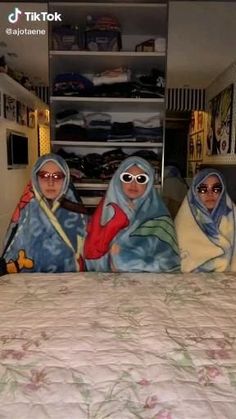 three women sitting on top of a bed covered in blankets