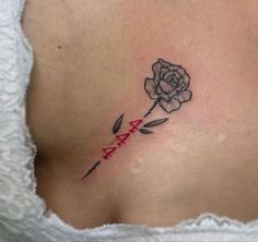 a woman's stomach with a rose tattoo on her side and the letter ax