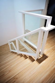 an empty room with wooden floors and white railings on the wall, in front of a glass door