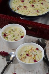 two bowls filled with soup sitting on top of a wooden table next to spoons