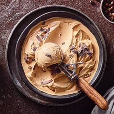 a bowl filled with ice cream next to some chocolate chips and nuts on the table