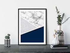 a white and blue abstract art print on a wall next to a potted plant