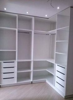 an empty closet with white shelves and drawers