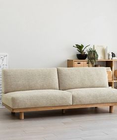 a beige couch sitting on top of a hard wood floor next to a white wall