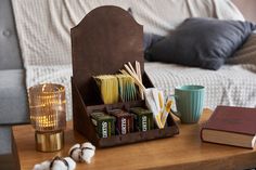 a coffee cup and some books on a table in front of a bed with pillows