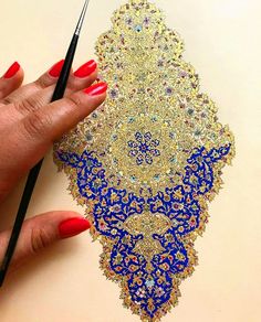 a woman's hand is holding a pencil and drawing an intricate design