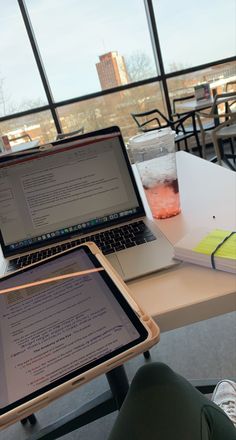 two laptops sitting on top of a table next to each other with drinks in front of them