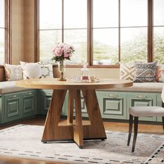 a kitchen with green cabinets and wooden table surrounded by chairs, windows, and rugs