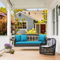 a blue couch sitting on top of a wooden porch next to a white fence and flowers