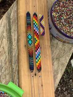 two colorful bracelets sitting on top of a wooden board