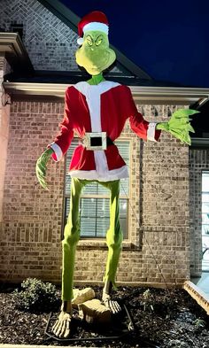 an inflatable grin costume standing on top of a pile of dirt next to a brick building