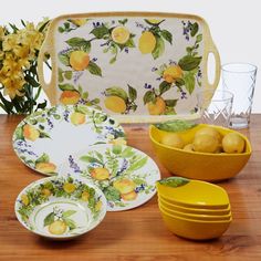 a table topped with plates and bowls filled with lemons on top of a wooden table