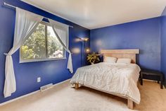 a bedroom with blue walls and white curtains