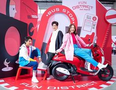 two people sitting on a red motorcycle in front of a sign