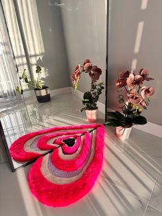 a pink rug sitting on top of a white floor next to a mirror and potted plants