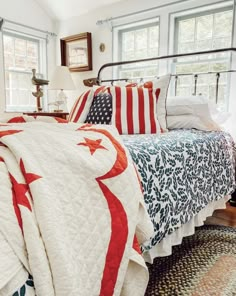 a bed with an american flag quilt on top of it next to a lamp and window