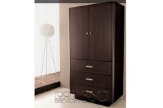 a tall brown cabinet sitting next to a mirror in a room with white walls and flooring