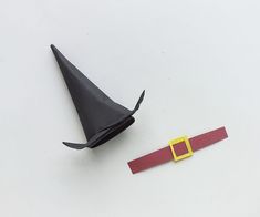 an origami hat next to a piece of paper with a yellow buckle on it