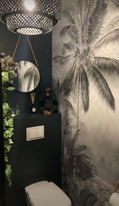 a bathroom with palm trees on the wall and a white toilet in front of it