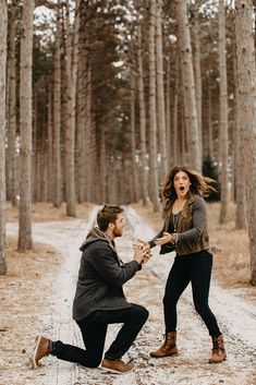 a man kneeling down next to a woman in the woods