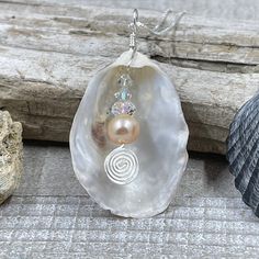 This beautiful pendant is made from a natural white oyster shell found on the beaches in the Cape May area. A spectacular metallic fresh water pearl is nestled inside the oyster shell showing off the treasure inside. The shell was then wire wrapped with sterling silver wire. The pendant measures 2 inches in length from the top of the bail and 1 inches wide. The pendant is on a 16" sterling silver box chain but other lengths are available in the below options. Silver Shell Necklace With Pearl Pendant, Silver Shell With Pearl Pendant, Handmade Silver Shell Pendant, Handmade Silver Pendant Shell, Silver Shell Jewelry With Pearl Charm, Silver Pearl Shell Necklace Gift, Silver Pearl Shell Necklace As A Gift, Silver Pearl Shell Necklace For Gift, Silver Mother Of Pearl Shell Gift