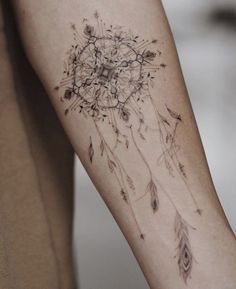 a woman's arm with a tattoo on it that has an image of a dream catcher