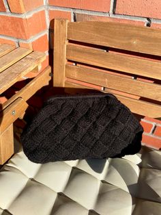 a pair of black socks sitting on top of a wooden bench next to a brick wall