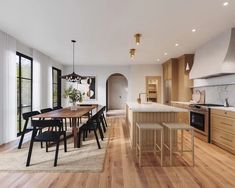 an open kitchen and dining area with hardwood floors, white walls, and large windows